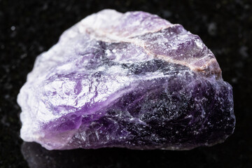 sample of unpolished amethyst mineral on black granite background close up from Russia