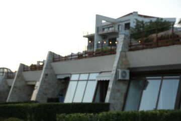 Luxury hotel building and green bushes outdoors, blurred view
