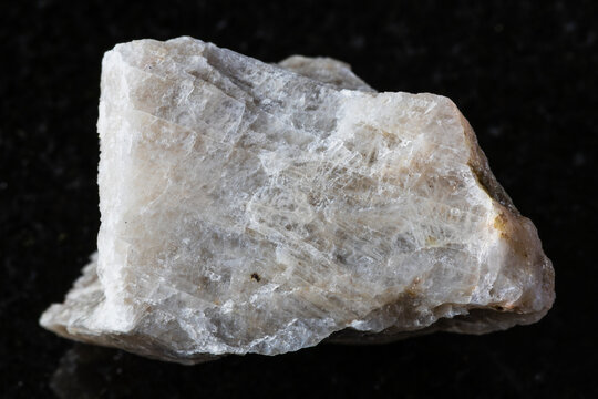 sample of raw oligoclase rock on black granite