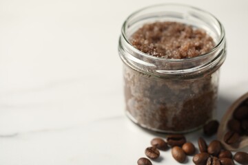 Natural body scrub and coffee beans on white table, closeup. Space for text