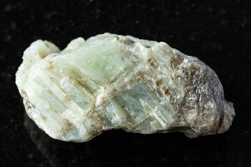 sample of raw beryl mineral on black granite