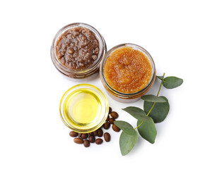 Natural body scrubs in glass jars, coffee beans, oil and eucalyptus branch isolated on white, top view