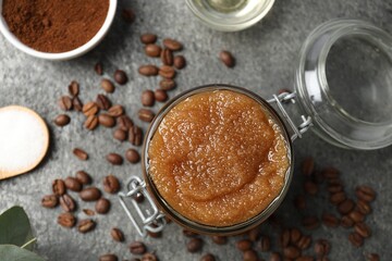 Natural body scrub in glass jar and ingredients on grey table, flat lay