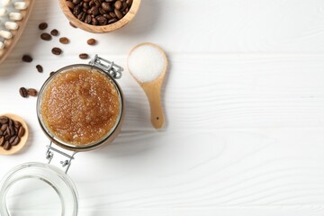 Natural body scrub in glass jar, ingredients and brush on white wooden table, flat lay. Space for text