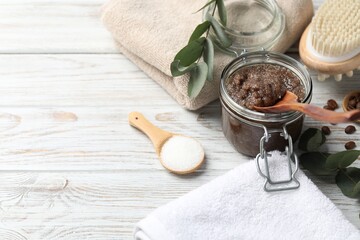 Natural body scrub in glass jar, ingredients, brush and towels on wooden table, closeup. Space for text
