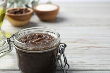 Natural body scrub in glass jar and ingredients on wooden table, closeup. Space for text