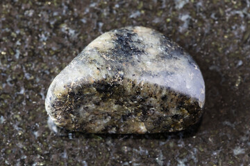 sample of tumbled diorite mineral on black granite