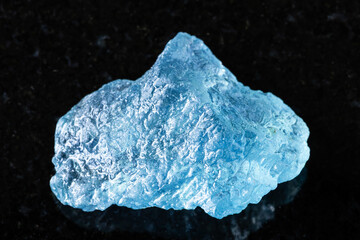 sample of raw aquamarine mineral on black granite