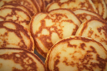 Golden thin pancakes or blini stacked on a plate for breakfast service