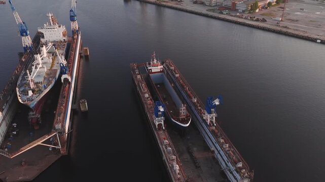 A shipyard in Riga, Latvia, with dry docks, cranes in motion, and workers moving. Captured during golden hour with industrial surroundings.
