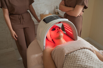 Estheticians overseeing red led light facial therapy in modern spa