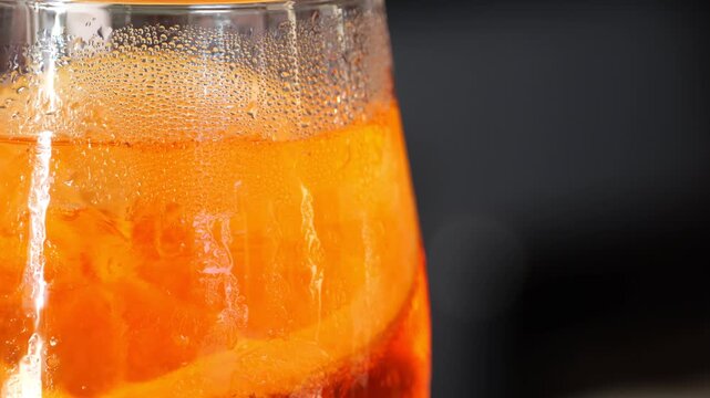 Bright orange aperol spritz, garnished with citrus slice and ice cubes