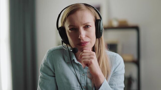 Pleasant woman wearing headset during video chat at home, first person view. Attractive lady with blond hair talking and gesturing during online conversation.