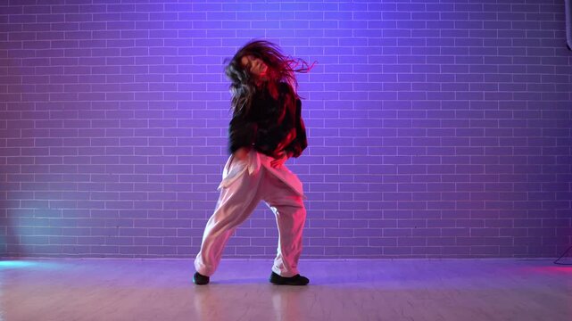 young girl choreographer dancing hip hop in neon lighting, woman performing on camera in and practicing dance in dark studio