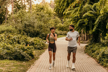 Happy couple running in park wearing sportswear, enjoying exercise together