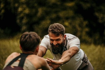 Personal trainer stretching with client outdoors in a park