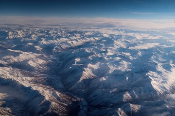 Obraz premium Snow-covered mountain range viewed from above during a clear daytime sky in winter