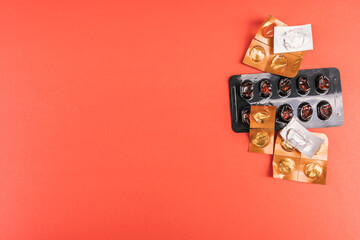 Empty pills and blister packs in various shapes on a vibrant red surface, top view