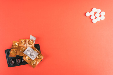 Empty pills and blister packs in various shapes on a vibrant red surface, top view