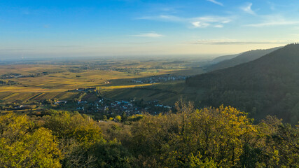 Naklejka premium Palatinate Forest, Germany: An aerial view from the edge of the Palatinate Forest, showcasing the transition from forested hills to the flat Rhine Valley, with a village and agricultural fields in the