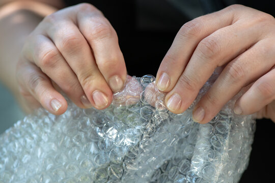 Female hands popping the bubbles in bubble wrap
