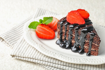 Piece of chocolate cake served with strawberries on white table, closeup