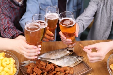 Friends with beer and snacks at wooden table, closeup