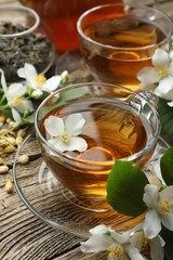 Aromatic jasmine tea in glass cups, brew and flowers on wooden table, closeup