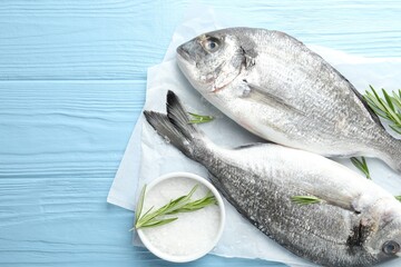 Fresh raw dourade fish with spices on blue wooden table, top view and space for text. Seafood delicacies