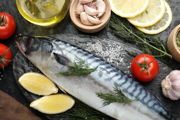 Fresh raw mackerel and spices on black table, flat lay. Seafood delicacies
