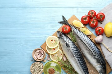 Seafood delicacies. Fresh raw mackerels and spices on light blue wooden table, flat lay. Space for text