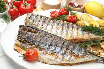 Tasty roasted mackerels with spices, tomatoes and potatoes on table, closeup. Homemade seafood dish