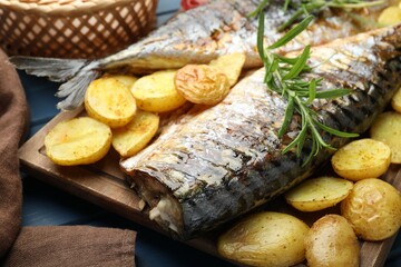 Tasty roasted mackerels with spices and potatoes on table, closeup. Homemade seafood dish