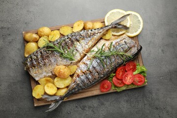 Tasty roasted mackerels with spices and vegetables on grey table, top view. Homemade seafood dish