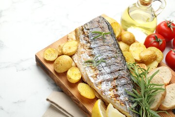 Tasty roasted mackerel with spices and vegetables on white marble table, above view. Homemade seafood dish