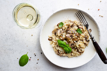 Risotto with mushrooms in a white plate over white background, top view