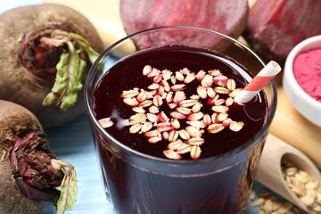Superfood. Tasty juice with oats in glass and beetroots on light blue table, closeup