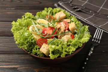 Delicious salad with croutons, chicken, egg, vegetables, lemon and arugula on wooden table, closeup