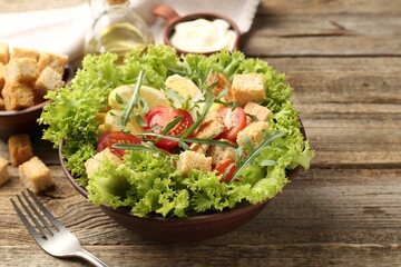 Delicious salad with croutons served on wooden table, closeup. Space for text