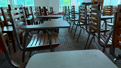 Wooden chairs arranged neatly create a classroom environment perfect for education or testing scenario