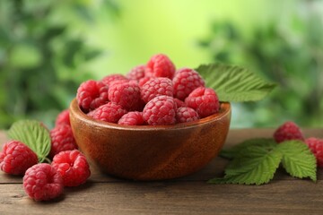 Tasty fresh ripe raspberries and leaves on wooden table, closeup