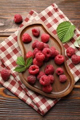 Tasty fresh ripe raspberries and leaves on wooden table, flat lay