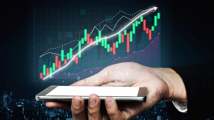 A hand holds a smartphone that showcases a financial graph with a rising trend, emphasizing business growth and technology in a modern urban landscape. Copula