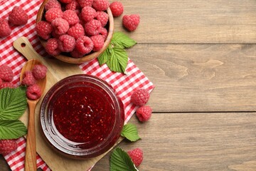 Tasty jam, fresh ripe raspberries and leaves on wooden table, flat lay. Space for text
