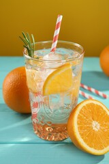 Refreshing soda water with ice and orange on light blue wooden table, closeup