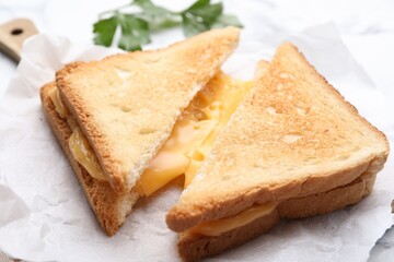 Tasty sandwiches with melted cheese and parsley on table, closeup
