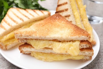 Tasty sandwiches with melted cheese and parsley on grey table, closeup