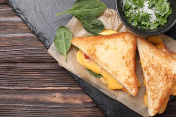 Delicious sandwiches with melted cheese and spinach on wooden table, top view. Space for text