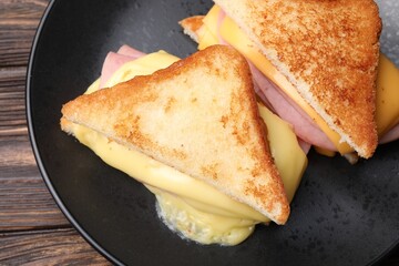 Delicious sandwiches with melted cheese and ham on wooden table, closeup