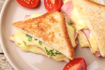 Delicious sandwiches with melted cheese, ham and tomatoes on table, closeup